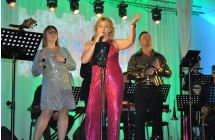 Trio wokalne na scenie. Obok nich zespół muzyczny.