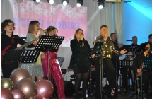 Muzycy z zespołu muzycznego. Na scenie wokaliści oraz instrumentaliści