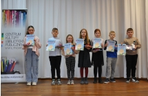 Siedmioro uczniów trzymających dyplomy oraz nagrody rzeczowe w konkursie na najładniejszą kartkę wielkanocną 