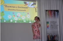 Dziewczynka stoi na scenie, opowiada wiersz na konkursie Recytatorskim 