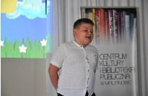 Uśmiechnięty chłopiec recytujący wiersz na scenie 