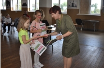 Kobieta wręczająca dziewczynce dyplom. 