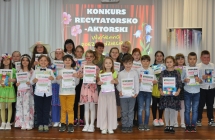 Kilkanaście dzieci oraz kobieta. Dzieci biorący udział w konkursie recytatorskim 