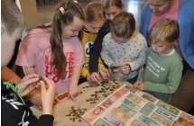 Grupa kilkunastu dzieci oglądających stare monety i banknoty 
