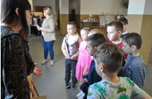 Dzieci i kobieta. Dzieci oglądają wystawę pasji, kobieta opowiada o kolekcji 