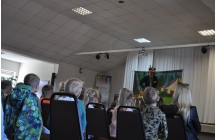Dzieic siedzą na krzesłach tyłem o aparatu, w tle na scenie mężczyzna w stroju wilka