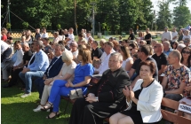 Publiczność oraz zaproszeni goście siedzący na ławkach pod sceną 