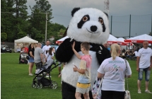 Wielka maskotka pandy i dzieci, które z nią się bawią 