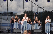 Kilkanaście dziewczynek tańczących na scenie. Ubrane mają kapelusze a'la smerfy 