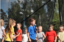 Dziewczynka śpiewająca do mikrofonu w towarzystwie tancerzy 