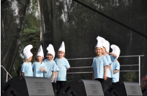 Grupa dzieci tańczących na scenie w strojach smerfów 