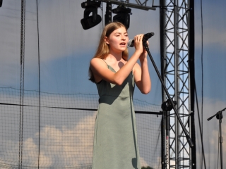 Dziewczynka śpiewa do mikrofonu na scenie 