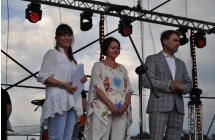 Dwie elegancko ubrane kobiety oraz mężczyzna w garniturze na scenie 