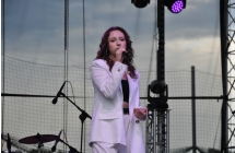 Kobieta w eleganckim stroju śpiewająca piosenkę na scenie 