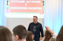 Mężczyzna mówiący do dzieci. Za nim slajd z napisem 