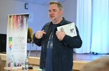 Mężczyzna mówiący i prezentujący książkę 