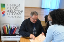 Kobieta i mężczyzna. Mężczyzna podpisuje kobiecie książkę