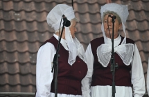 Dwie kobiety śpiewające do mikrofonu. Ubrane w ludowe stroje 