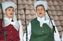 Dwie kobiety śpiewające do mikrofonów na scenie. 