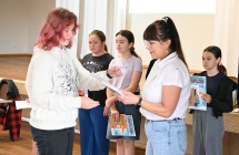 Kobieta wręczająca dyplom oraz nagrodę młodej dziewczynie 