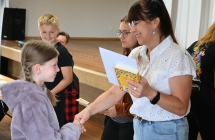 Kobieta wręczająca dyplom i nagrodę uczennicy 