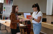 Kobieta wręczająca dyplom i nagrodę uczennicy 