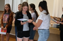 Kobieta wręczająca dyplom i nagrodę dziewczynce 