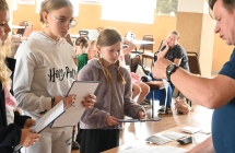 Mężczyzna wręczający karki z zagadkami trzem dziewczynkom 