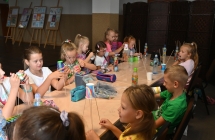 Grupa kilkunastu dzieci wykonujących prace plastyczne 