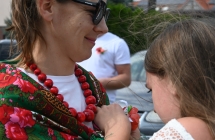Dziewczynka przypina kobiecie kotylion do koszuli 