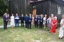 Kilkanaście osób pod budynkiem kościoła, elegancko ubrane kobiety i mężczyźni