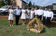 Grupa osób przy wieńcu dożynkowym 