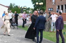 Dwoje mężczyzn podających sobie rękę na tle budynku kościoła. Dookoła w tle wiele osób 