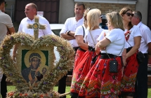 Wieniec dożynkowy, obok kilkanaście osób . 