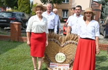Dwie kobiety i dwoje mężczyzn przy wieńcu dożynkowym