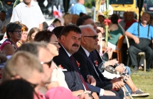 Zaproszeni goście dożynkowi siedzący na ławce przed sceną 