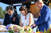 Dwoje mężczyzn i kobieta podczas krojenia chleba dożynkowego 