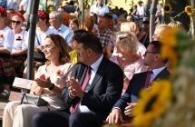 Goście dożynek siedzący na ławce przed sceną