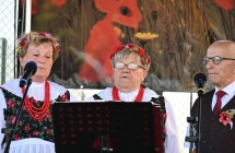Dwie kobiety i mężczyzna w ludowych strojach występujący na scenie 