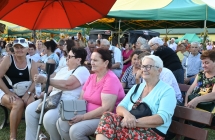 Goście dożynek siedzący na ławce przed sceną 