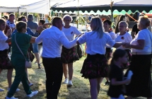 Kilka osób bawiących się do muzyki. Tańczą w kółku 
