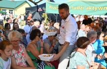Mężczyzna częstujący gości chlebem dożynkowym 
