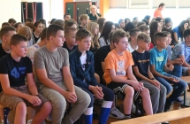 Grupa kilkudziesięciu uczniów siedzących na ławkach 