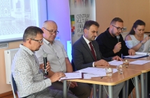 Kobieta i czworo mężczyzn. Jeden z nich czyta do mikrofonu 