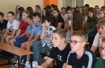 Kilkudziesięcioro dzieci siedzących na ławkach
