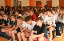 Kilkudziesięcioro dzieci siedzących na ławkach