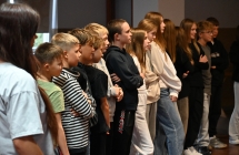 Grupa kilkunastu młodych osób podczas obserwacji lekcji samoobrony