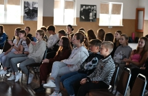 Grupa kilkudziesięciu młodych osób słuchających prelekcji gościa 