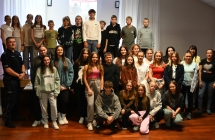 Grupa kilkudziesięciu dzieci i młodzieży podczas zdjęcia grupowego. Wszyscy stoją na scenie.