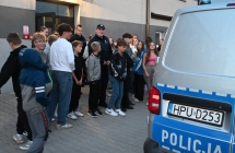 Grupa młodzieży słuchająca policjantów przy wozie policyjnym 